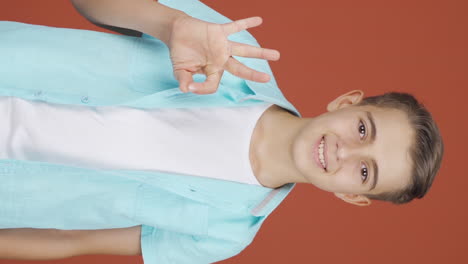 Vertical-video-of-Boy-making-positive-gesture-at-camera.